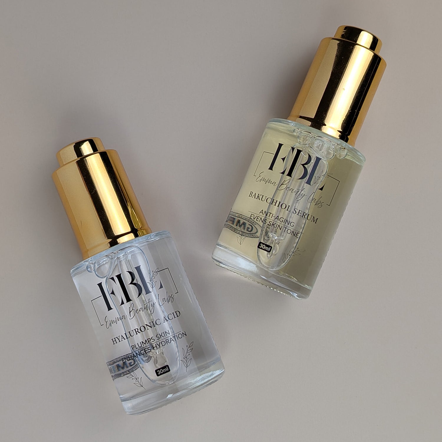 Two serums laying down. Hyaluronic Acid Serum and Bakuchiol Serum.