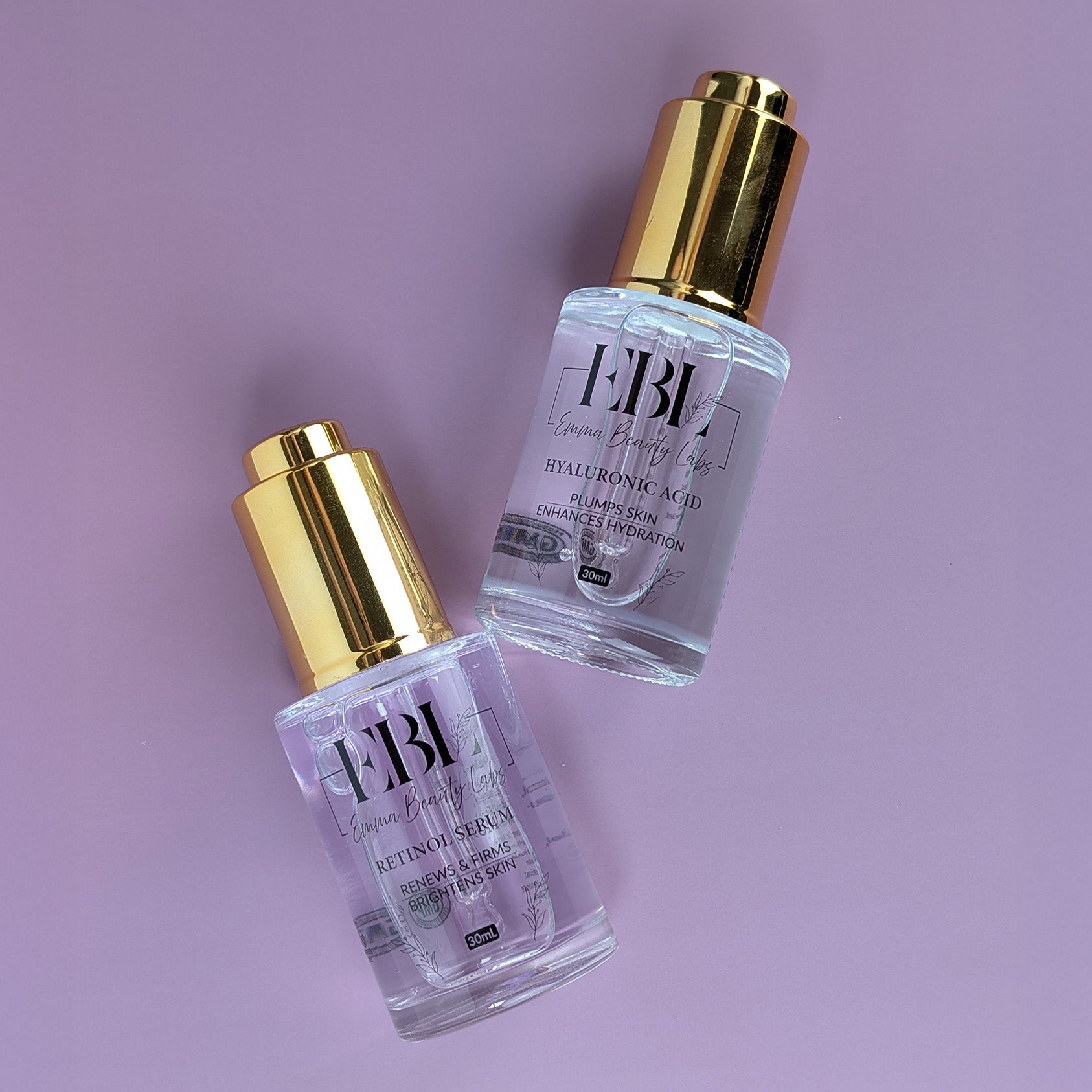 Two serums laying down. Hyaluronic Acid Serum and Retinol Serum.
