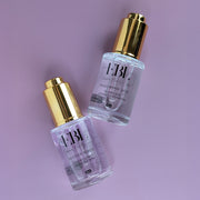 Two serums laying down. Hyaluronic Acid Serum and Retinol Serum.